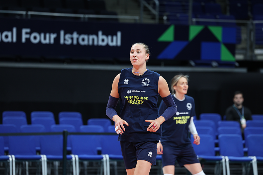 Female volleyball player in a navy uniform on an indoor court with a 'Final Four Istanbul' banner in the background.
