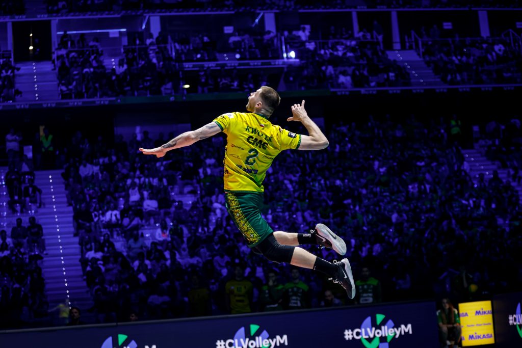 007 The Volley Lovers Male volleyball player in a yellow jersey jumping mid-air against a packed arena crowd.