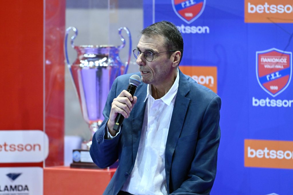 02 The Volley Lovers Man in a blue blazer speaks into a handheld microphone at a sports event booth with Betsson signage in the background.