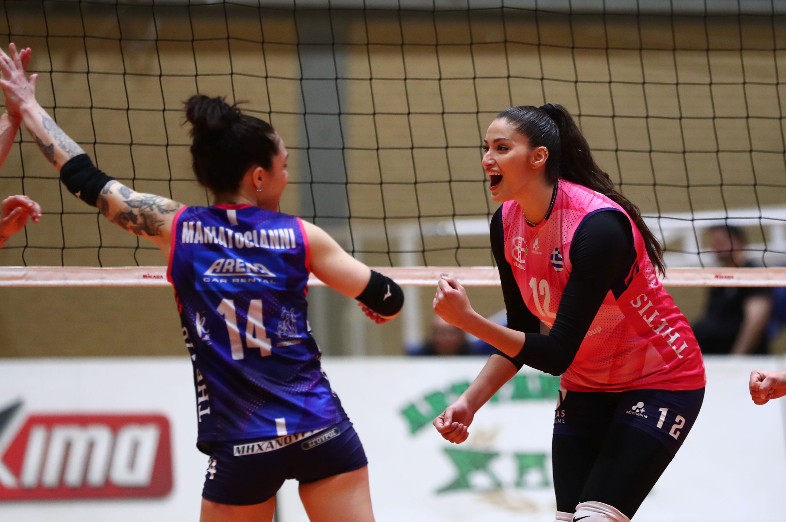 05113985 The Volley Lovers Two female volleyball players high-fiving at the net during a match.