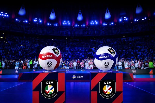 Two large Mikasa volleyballs perched on red-and-navy pedestals in a packed arena, blue stage lights for CEV EuroVolley 2026.