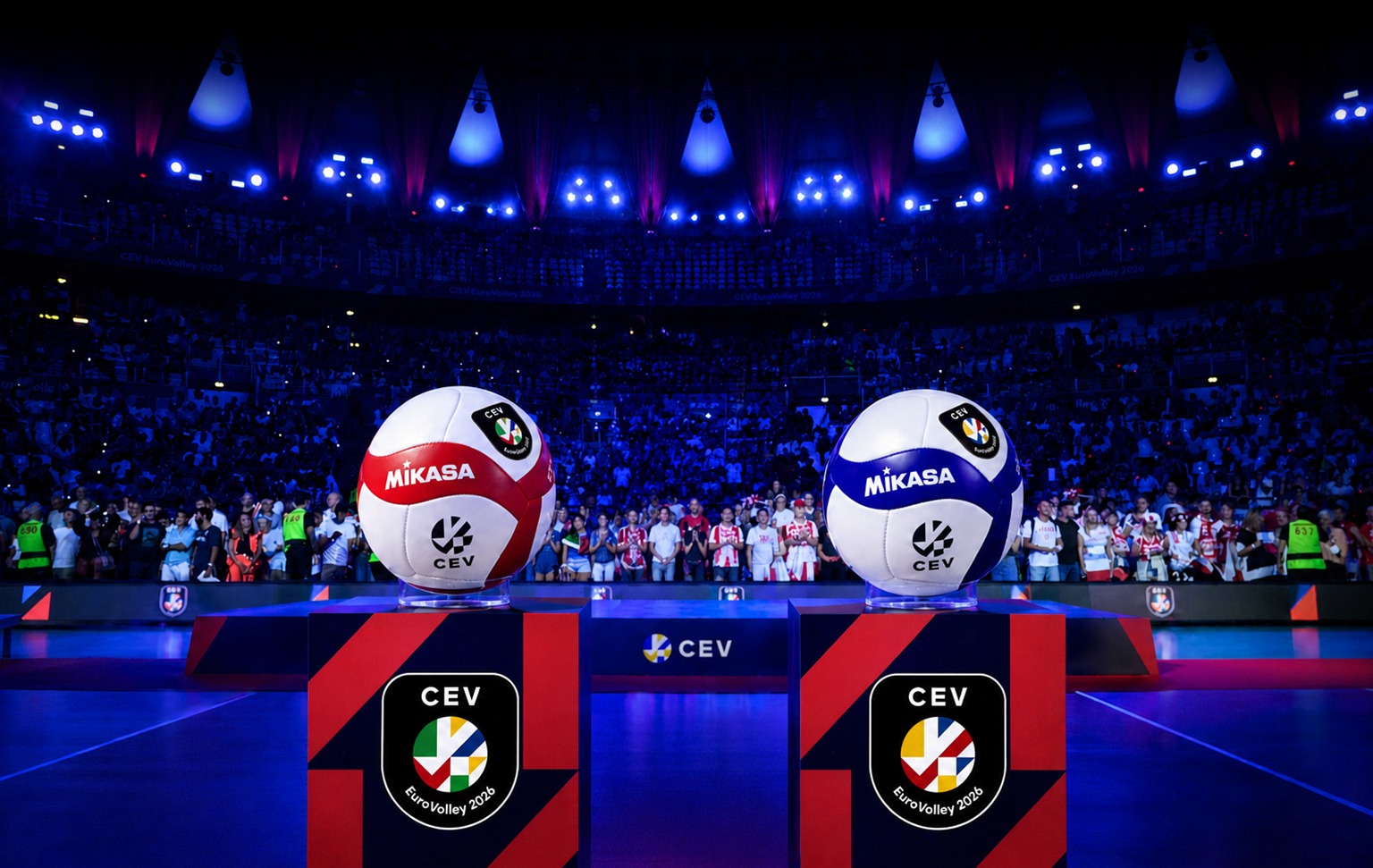 71074572319443173662483258443786572097776181n The Volley Lovers Two large Mikasa volleyballs perched on red-and-navy pedestals in a packed arena, blue stage lights for CEV EuroVolley 2026.