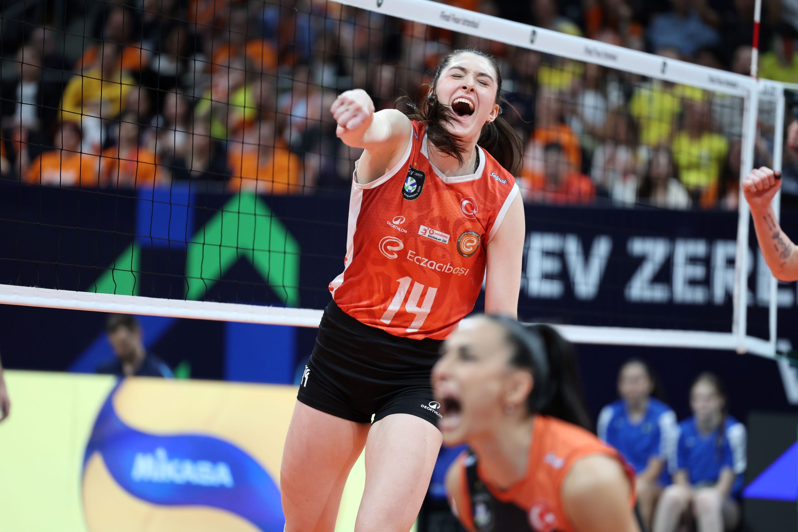 IMG9083 The Volley Lovers Volleyball player in orange jersey (#14) celebrates a point at the net with cheering crowd in background.