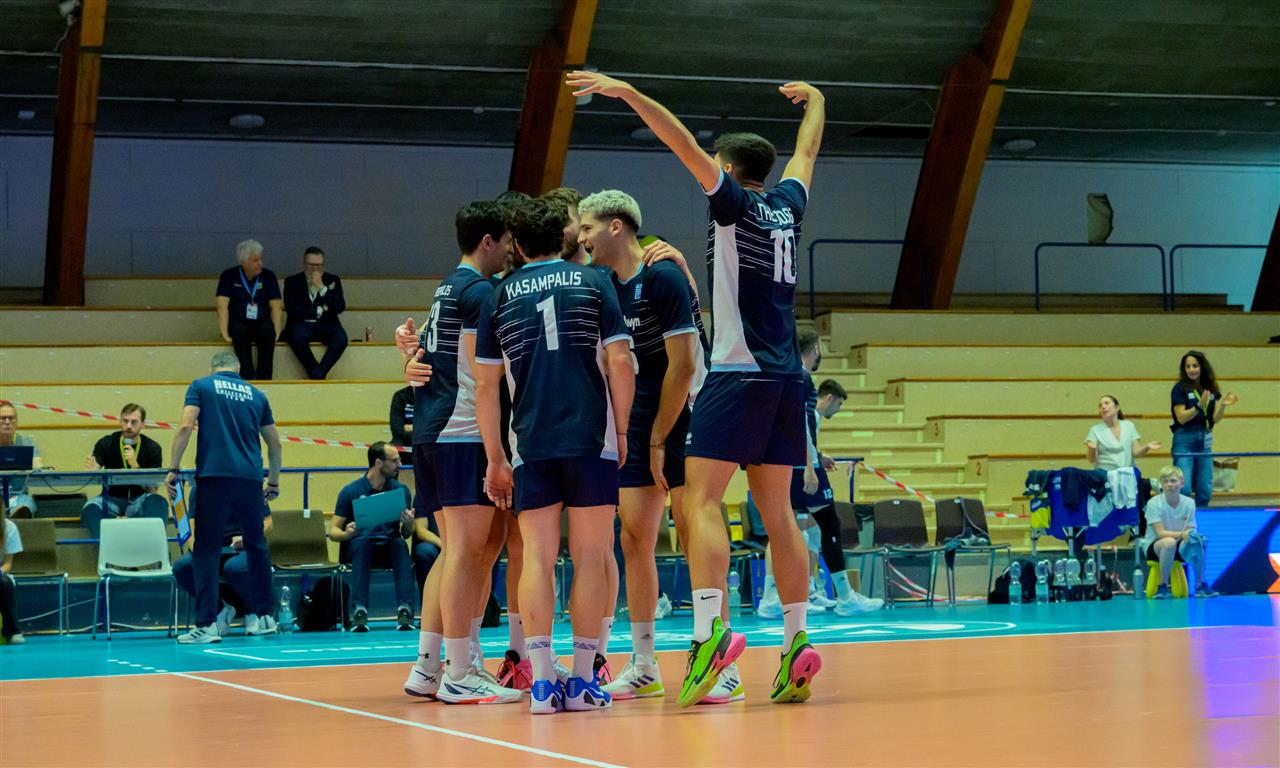 004 The Volley Lovers A group of male volleyball players in blue uniforms huddle and celebrate on an indoor court.