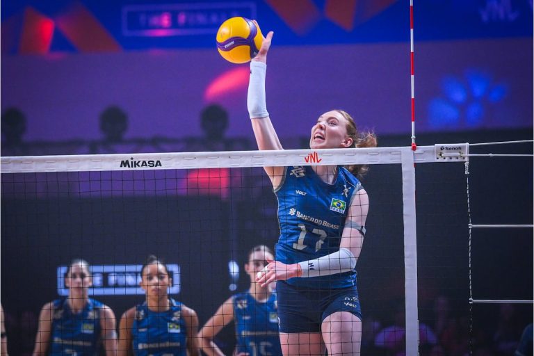 004 The Volley Lovers Brazilian female volleyball player in a blue uniform jumps to spike a yellow ball over the net during a match.