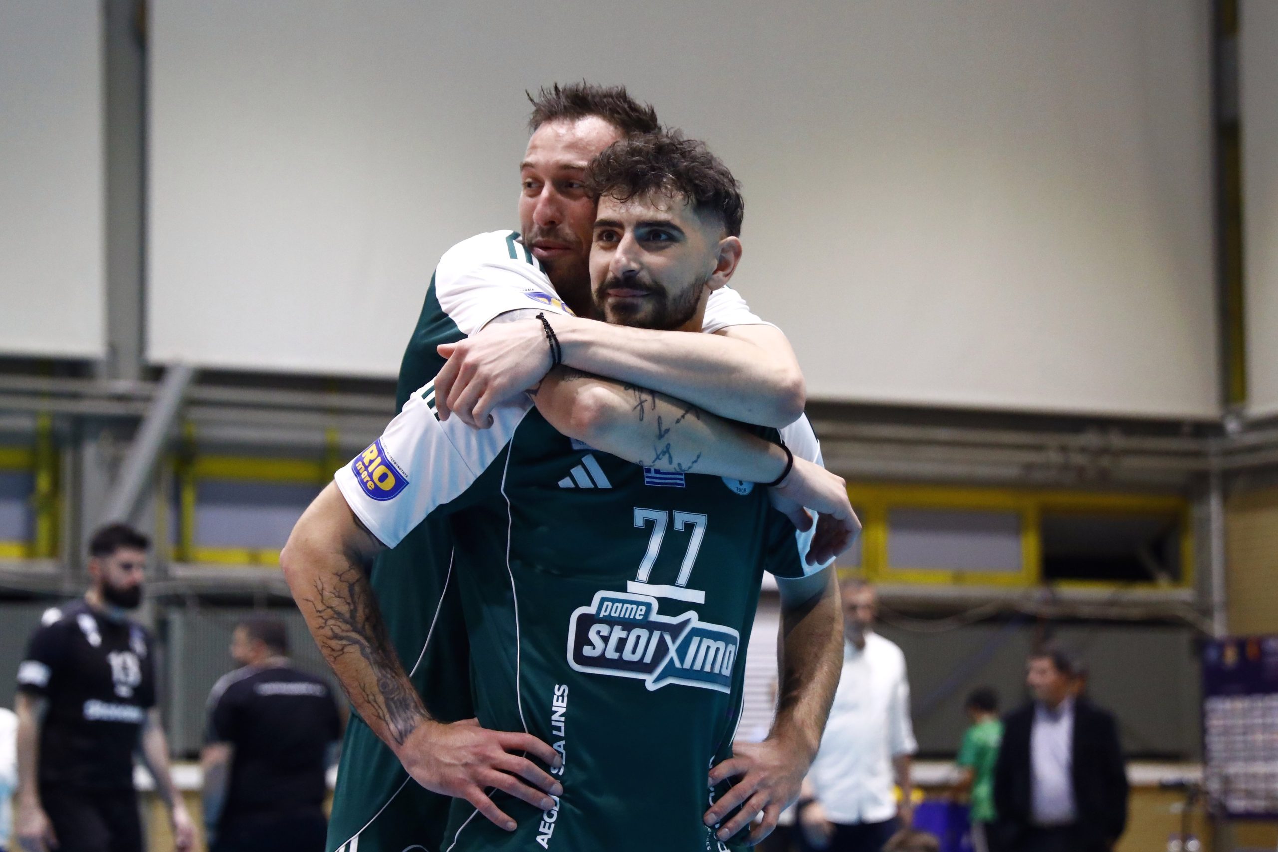 ÐÁÍÁÈÇÍÁÉÊÏÓ ÐÁÏÊ<br>1ïò ÔÅËÉÊÏÓ ÐËÅÉ ÏÖ VOLLEY LEAGUE 20252026 The Volley Lovers Two male teammates in green uniforms share a hug in an indoor sports venue, cheering after a game.