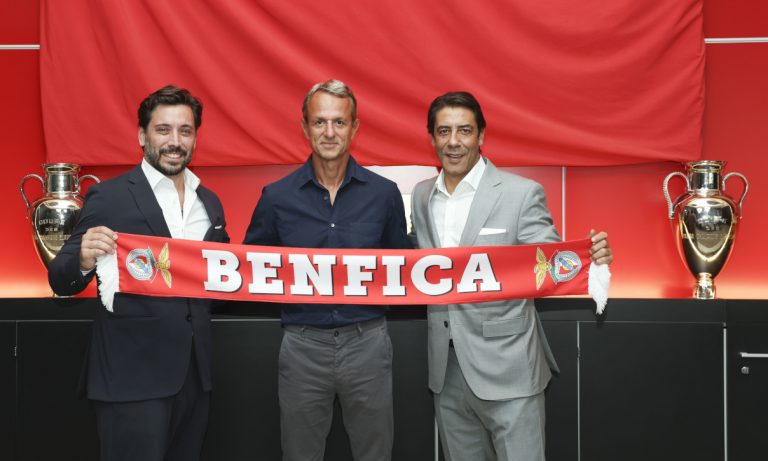 apresentacaonew The Volley Lovers Three men in suits pose together, holding a red Benfica scarf in front of two silver trophies in a bright room.