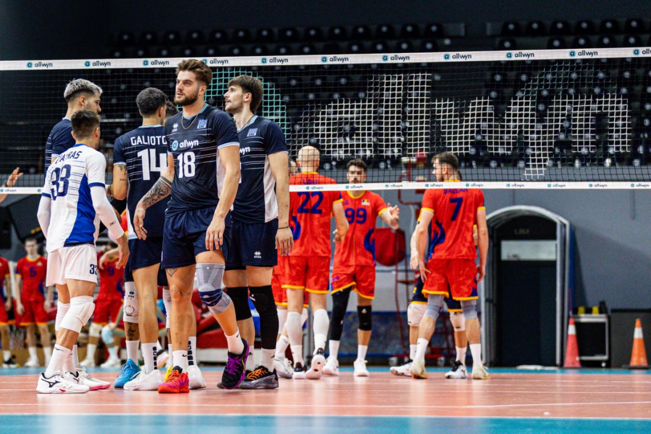 Indoor volleyball scene with players from blue and red teams gathered near the net on a court in a arena.