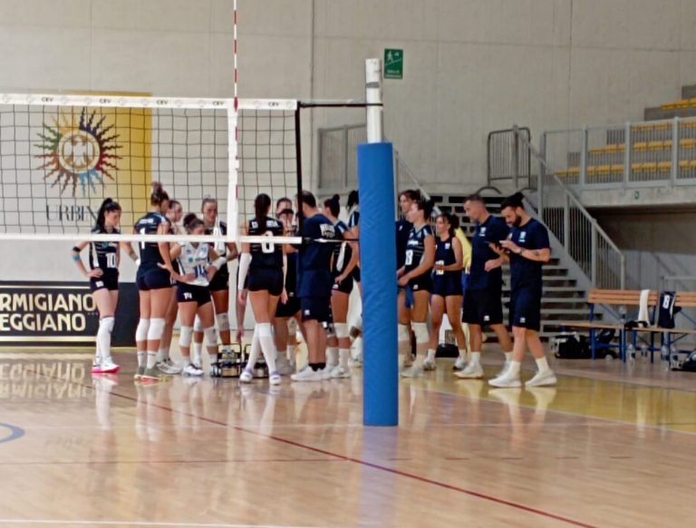 wnnt2026friendlyvssweden The Volley Lovers Volleyball team in blue uniforms huddling near the net on an indoor court.