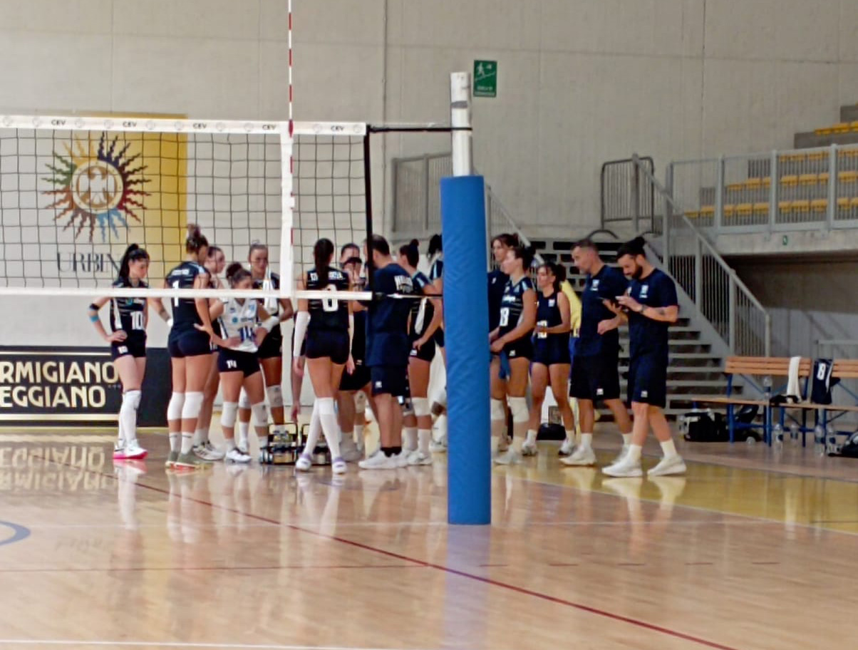wnnt2026friendlyvssweden The Volley Lovers Volleyball team in blue uniforms huddling near the net on an indoor court.