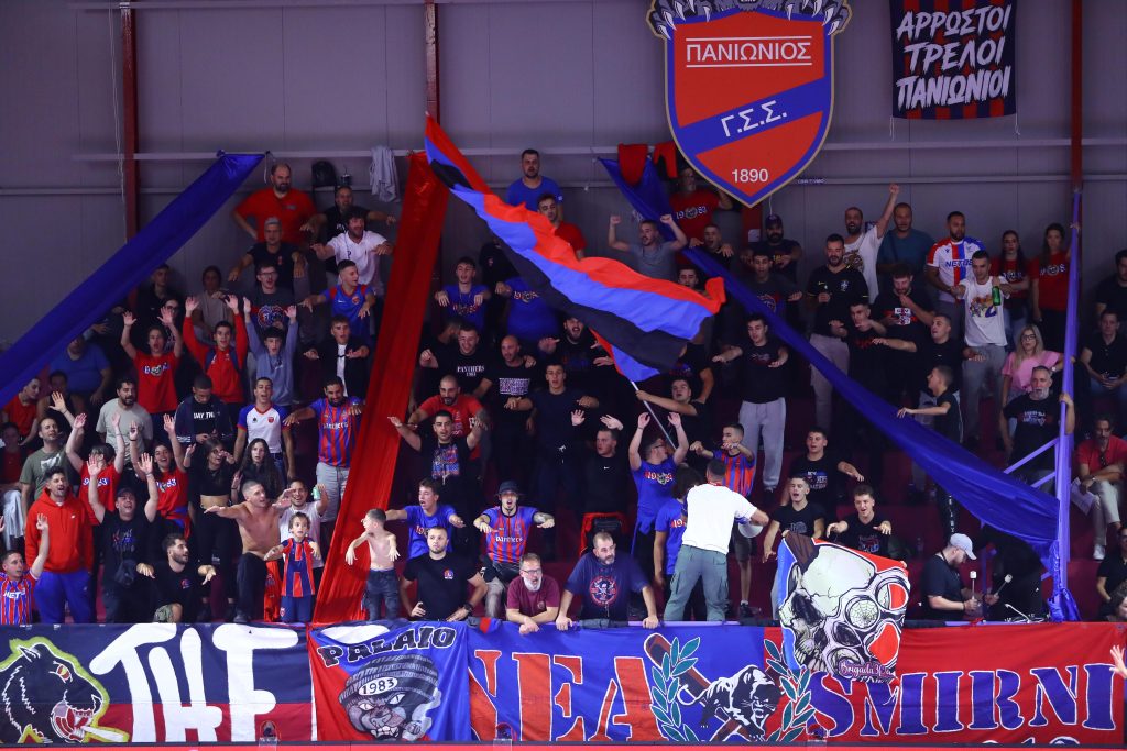 5357002 The Volley Lovers Crowd of sports fans cheering in a stadium, waving red and blue banners and flags.