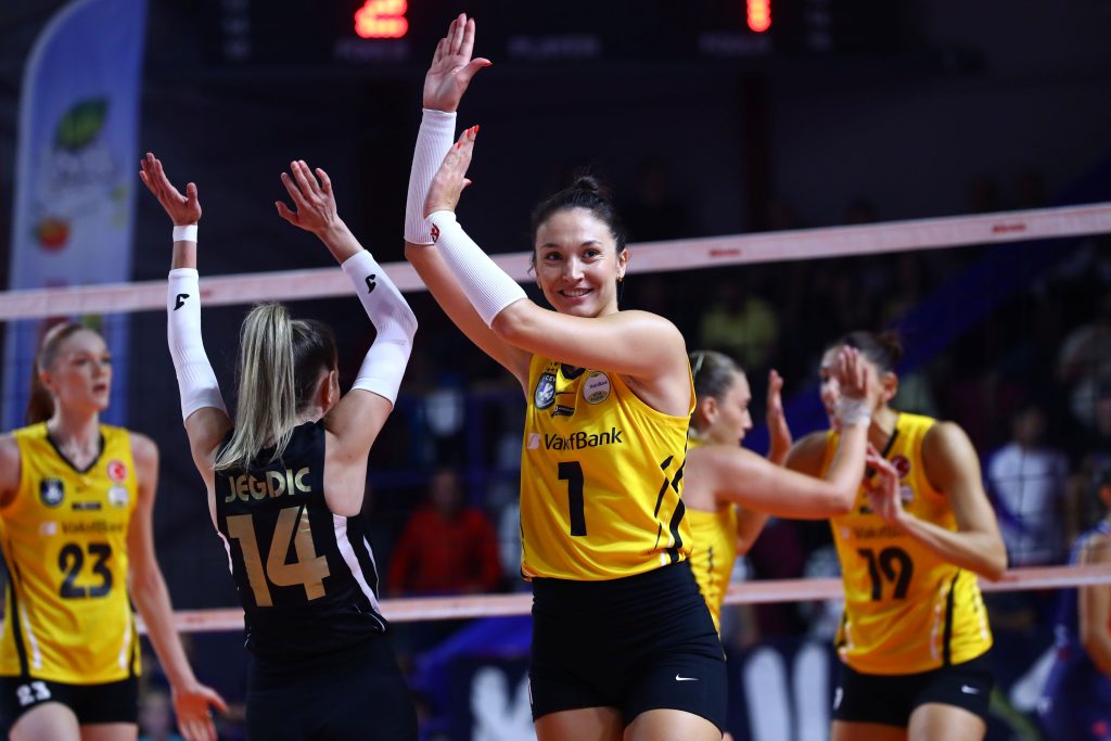 5357275 The Volley Lovers Female volleyball players in yellow uniforms high-fiving near the net after a point in a match.