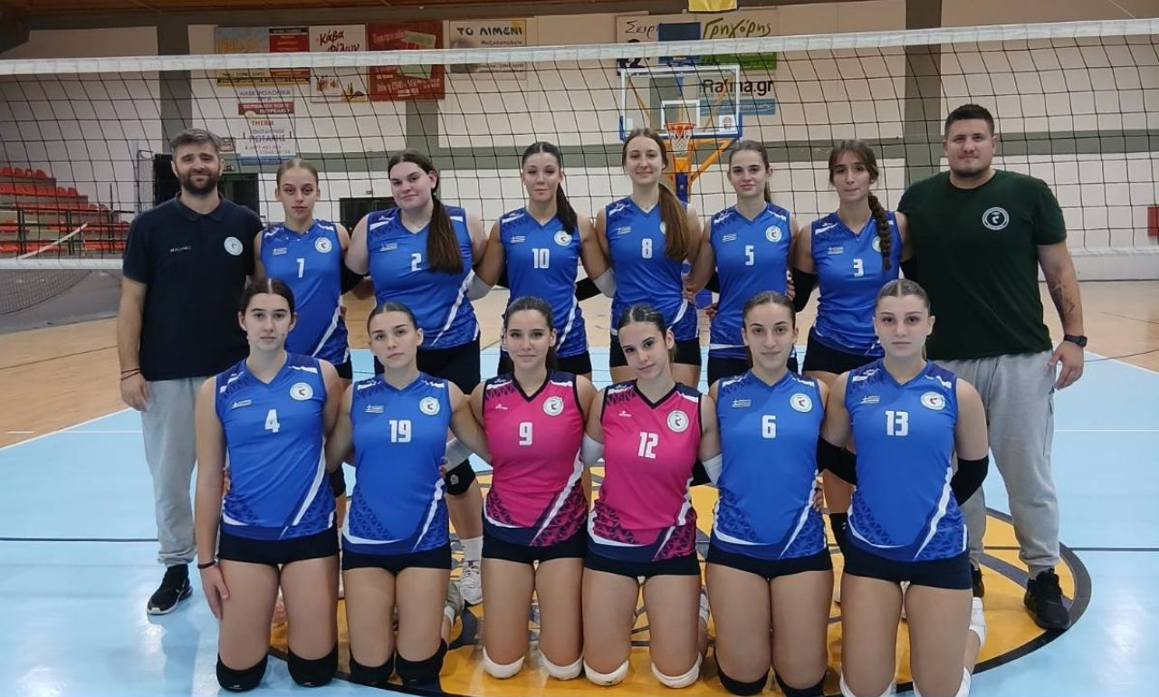 02 The Volley Lovers Girls' volleyball team posing for a group photo on the court, wearing blue uniforms with numbers, two players in pink jerseys kneeling in front.