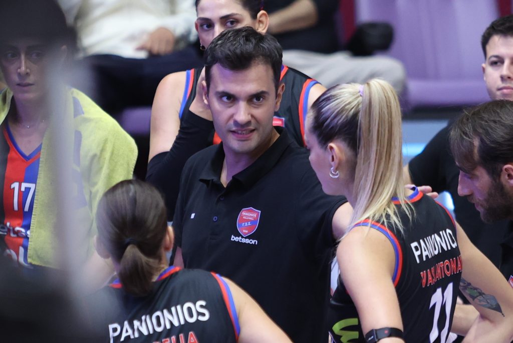 Intime Kamsis Dimosthenis The Volley Lovers Group of volleyball players in dark jerseys with blue‑red trim, gathered together indoors, backs showing PANIONIOS and player numbers.