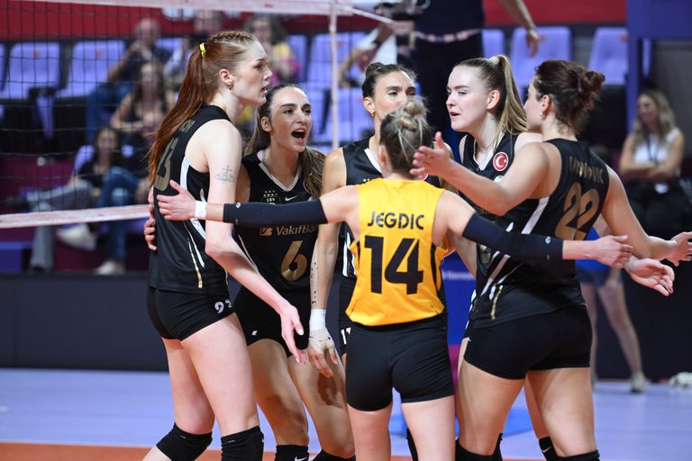 5359788 The Volley Lovers A group of female volleyball players in black uniforms huddle together in celebration on the court, arms around each other.