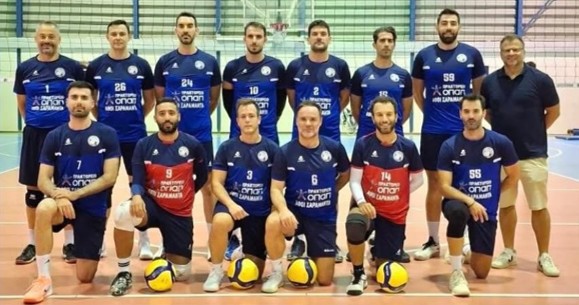 Δελτίο Τύπου 13102026 Κύπελλο Ανδρών 1η αγωνιστική The Volley Lovers Group of volleyball players in blue uniforms posing for a team photo in a gym, with a coach standing on the right edge.
